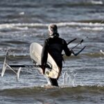 Kitesurfista in azione su un'onda, evidenziando la bellezza e i rischi dello sport acquatico.